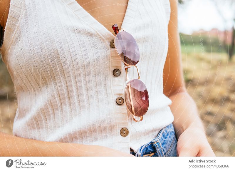 Anonymous woman with sunglasses hanging from her shirt fashion model person young girl beautiful summer posing stylish female white adult concept hand holiday