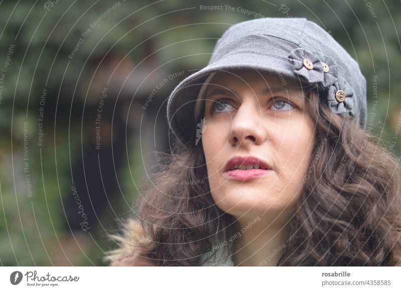 young woman with cap looks up thoughtfully Woman Cap Upward Meditative think expect full of worries Worries Concern expectant Expectation portrait Face