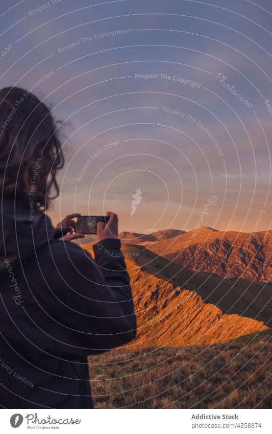 Unrecognizable traveling man taking photo of mountains on smartphone in evening hiker take photo highland range sunset memory male wales united kingdom uk