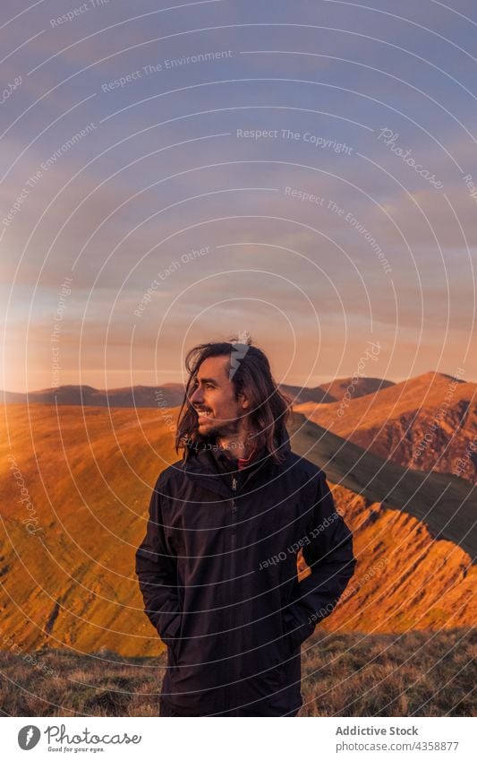 Happy traveler admiring view of mountains at sunset happy viewpoint admire smile trekking observe looking away highland hiker adventure wales united kingdom uk