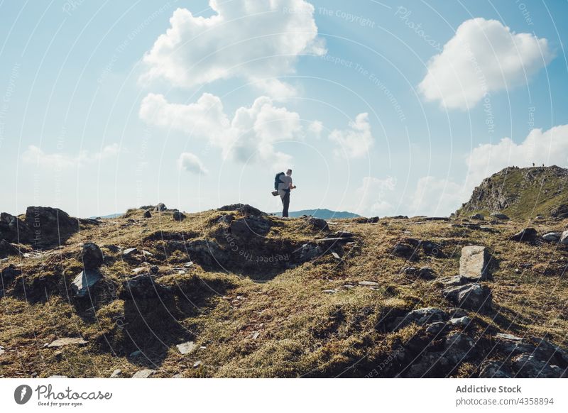 Traveling man with backpack standing in rocky mountains on sunny day hiker trekking traveler highland wanderlust male wales united kingdom uk great britain