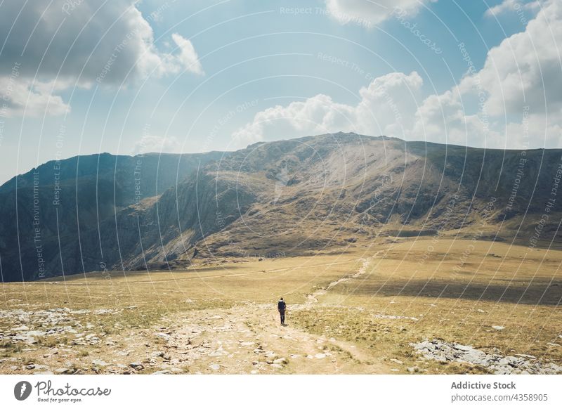 Unrecognizable traveler walking on road in mountainous valley hiker trekking highland summer sunny wales united kingdom uk great britain adventure nature