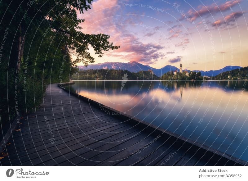 Wooden promenade near lake in mountains at sunset boardwalk embankment pond highland evening sundown slovenia landscape tranquil calm dusk scenic nature sky