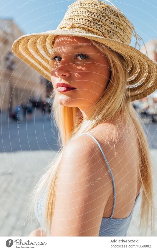 Woman in straw hat on sunny day in city woman summer sunhat charming summertime style street female sunlight trendy holiday carefree lady young feminine blond