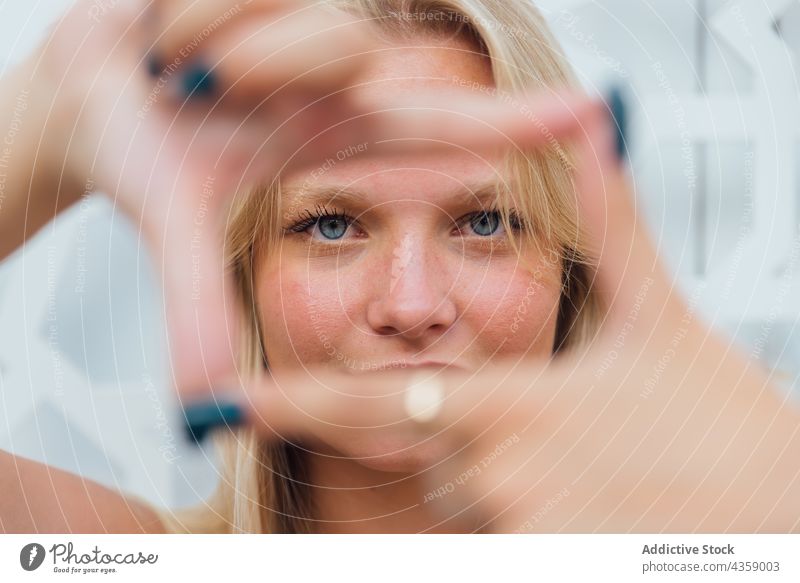 Charming woman showing framing gesture in city frame sign charming blond symbol photo hand female content demonstrate creative imagination inspiration serene