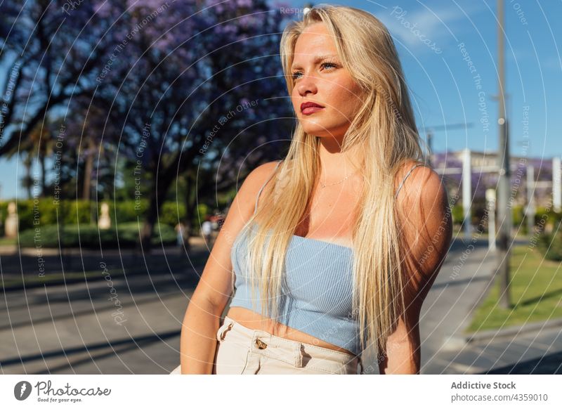 Stylish woman standing in street on sunny day looking away trendy charming city summer style outfit urban appearance female individuality beautiful confident