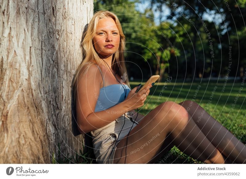 Woman listening to music on mobile phone in summer park woman smartphone sunset song female enjoy carefree using device earphones gadget cellphone tranquil