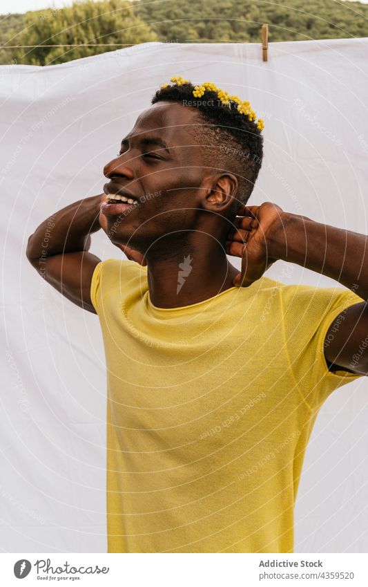 Happy black man with yellow flowers in hair wildflower color trendy bloom male ethnic african american style model fashion appearance handsome cool flora plant