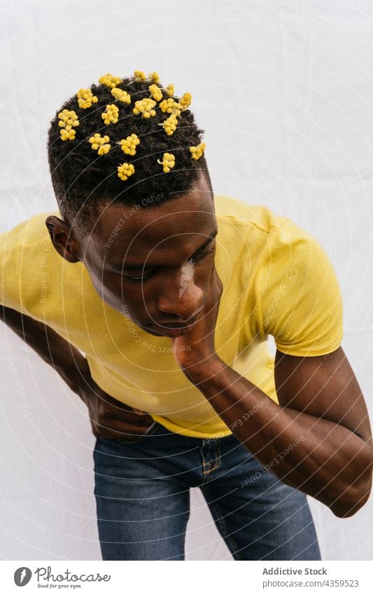 Serious black man with yellow flowers in hair wildflower color serious trendy bloom male ethnic emotionless african american style model unemotional pensive