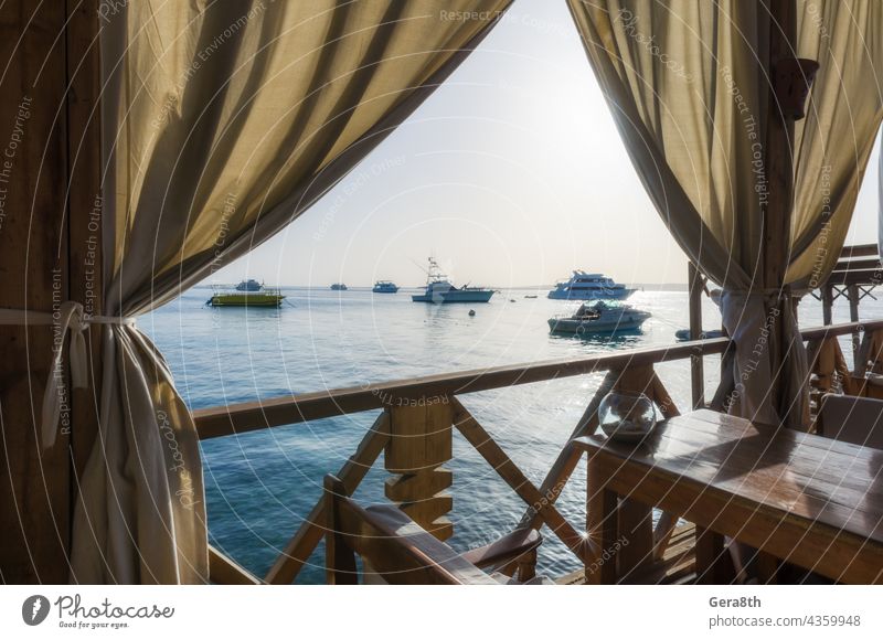 Parasols and palm trees on the background of the red sea and ships in Egypt Hurgahada Red Sea sharm el sheikh Bay Beach Blue boat Boating trip coast Cruise Trip