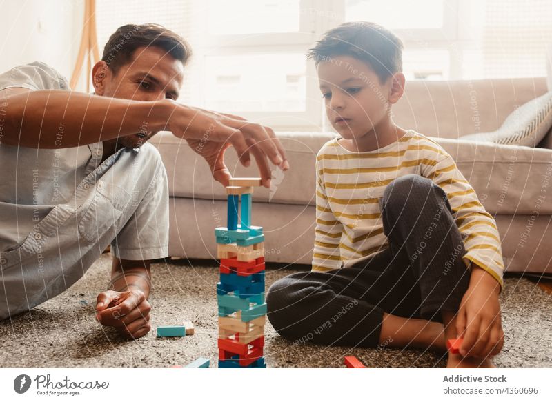 Father and son playing with construction pieces in the dining room child father block brick together toy boy family man childhood education game smile build