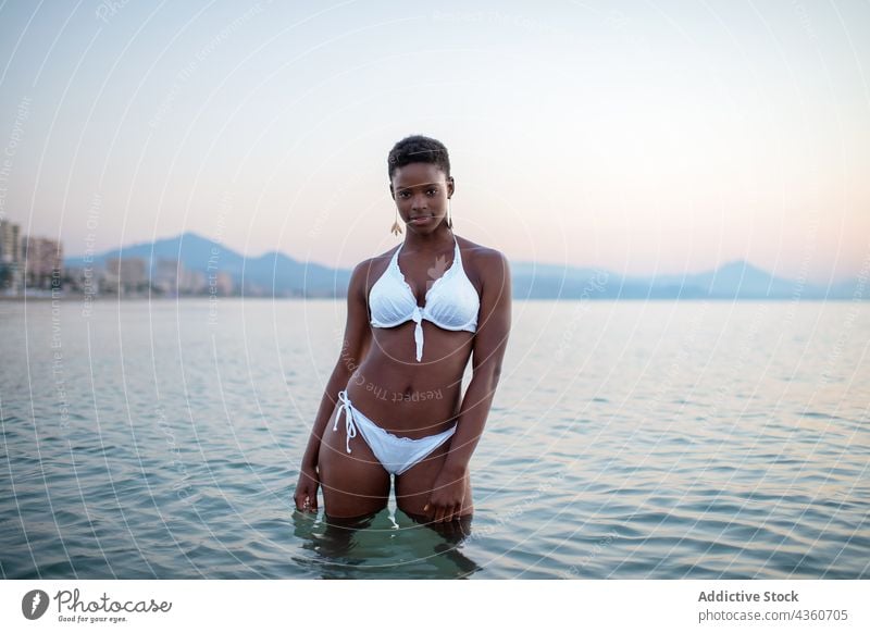 Black woman with short hair in the sea water sunset ripple sundown evening summer female ethnic black african american tranquil beautiful relax carefree holiday