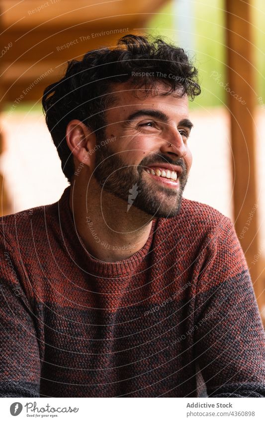 Cheerful man chilling on terrace and looking away cheerful handsome appearance weekend vacation relax smile male pyrenees rest style happy house enjoy positive