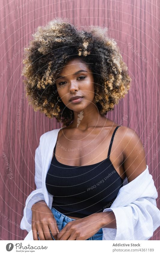 Stylish black woman standing near colorful door style cool confident self assured millennial charismatic personality serious female staircase young afro jeans