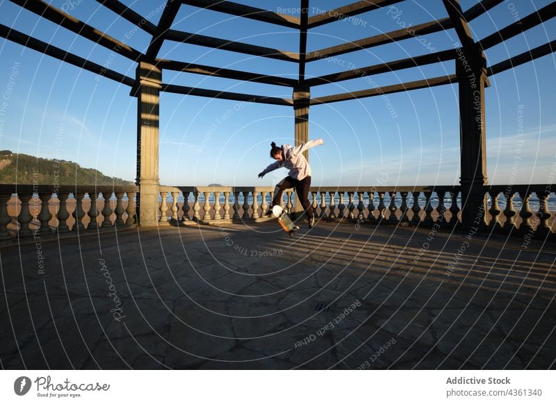 Man showing trick and jumping with skateboard man stunt active skater perform skill male energy activity sport motion summer hobby sporty cool terrace seaside