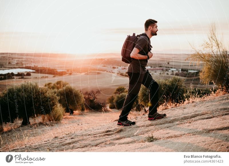 backpacker man hiking in peak of mountain at sunset enjoying landscape. Lifestyle and nature adventure travel wanderlust dawn flare young adult caucasian