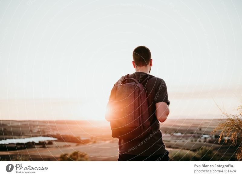 back view of relaxed hiker man with backpack at sunset in mountain. Hiking and nature backpacker hiking adventure travel wanderlust dawn flare young adult