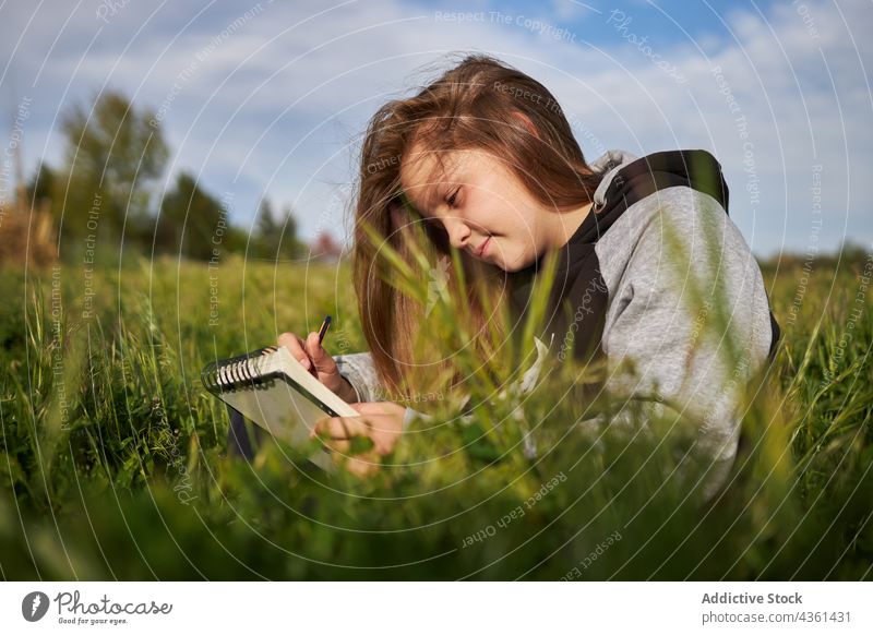 Cheerful girl drawing in notebook in field sketchbook countryside enjoy creative teenage summer smile happy nature sit grass carefree season cheerful create art