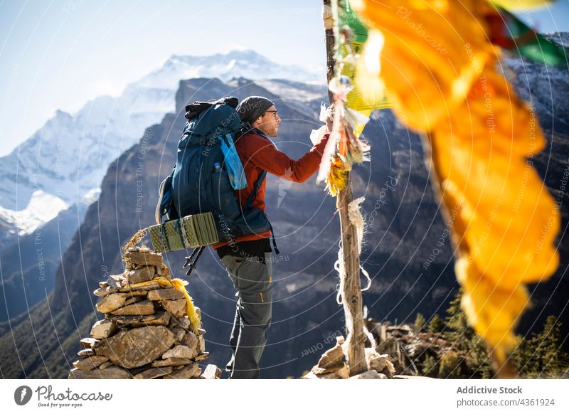 Traveling man hanging prayer flag in mountains traveler buddhist adventure highland male himalayas nepal freedom buddhism religious holy sacred tradition