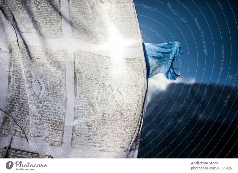 Part of white prayer flag fluttering in wind in mountains buddhist religion buddhism tradition highland himalayas nepal color sunny sunlight national symbol