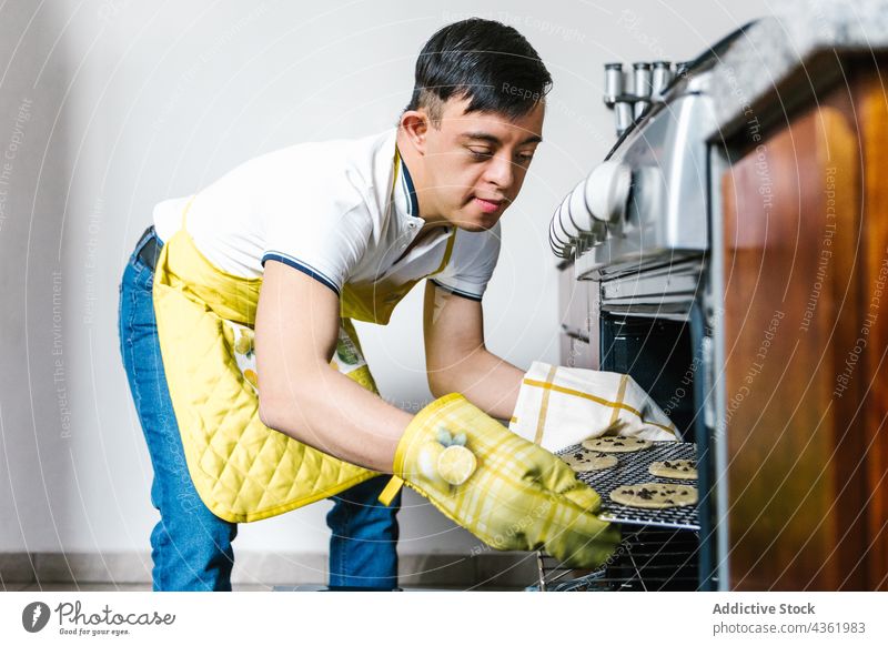 Latin teen boy with Down syndrome preparing cookies in kitchen down syndrome oven prepare disorder mental dessert ethnic latin teenage pastry sweet bake food