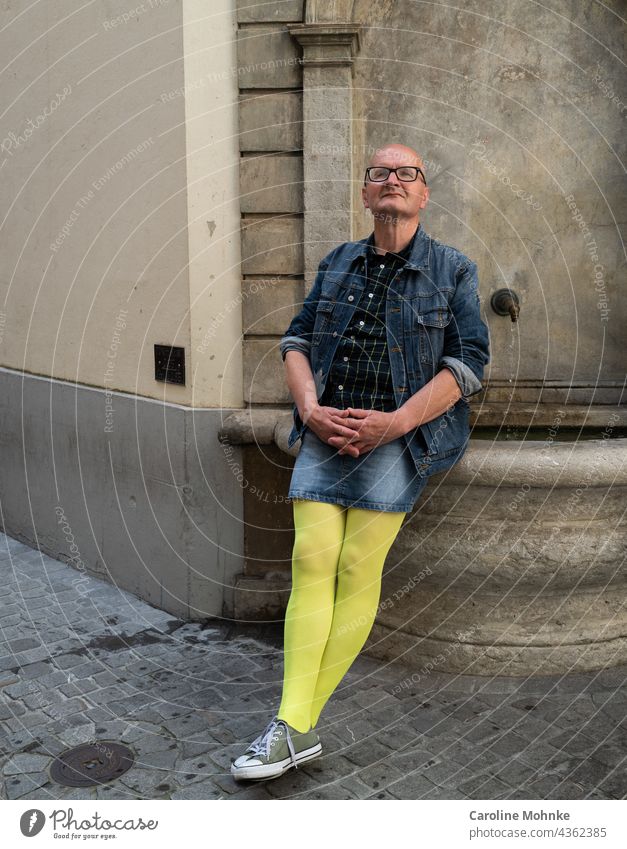 Man in jeans mini and yellow pantyhose sits on a fountain and looks satisfied Fashion Fashion Model Lifestyle Style Face Skirt support Human being Happy Well