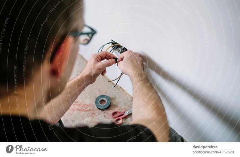 Electrician working on the electrical installation of a house electrician unrecognizable electrical technician connecting wrapping electrical tape protecting