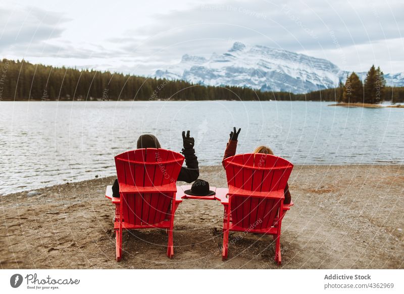 Unrecognizable travelers gesturing V sign near lake shore deckchair v sign together rest nature water gesture two jack lake alberta canada banff national park