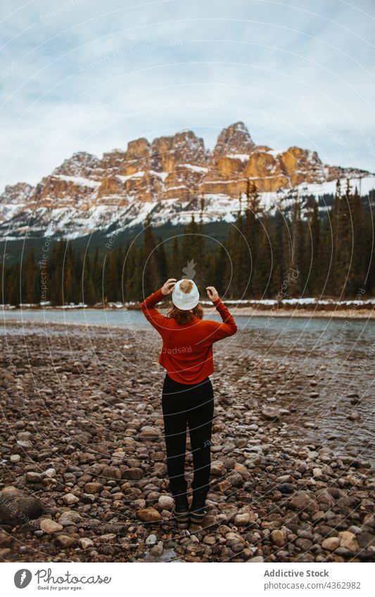 Unrecognizable woman tourist admiring mountain and forest admire shore river female nature tree snow coniferous castle mountain banff national park alberta