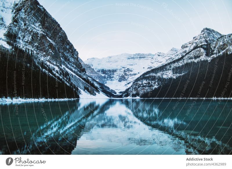 Calm lake reflecting snowy mountains winter reflection shore calm clean sky cloudy lake louise banff national park alberta canada water ridge nature range