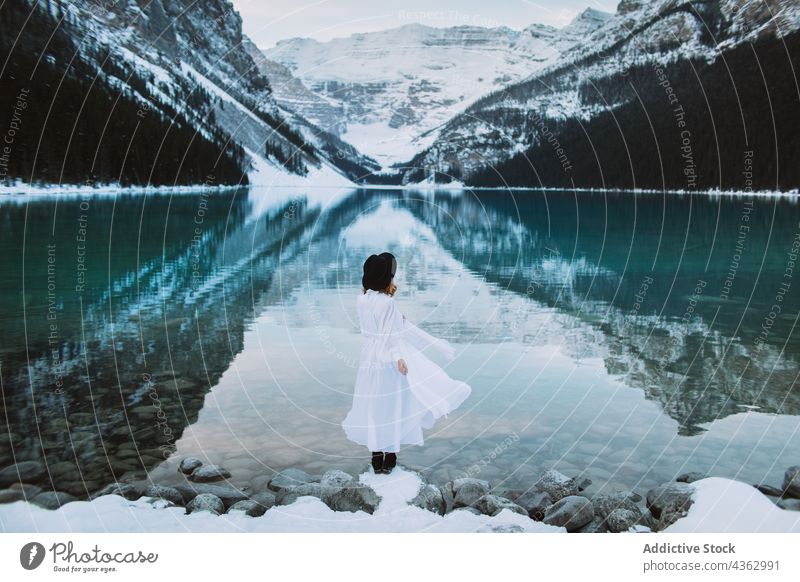 Unrecognizable woman standing towards lake in winter shore mountain nature snow cold travel lake louise banff national park alberta canada water clean ridge