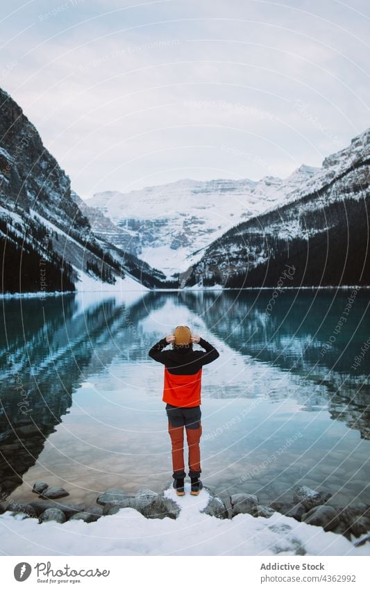 Unrecognizable tourist standing on shore of calm lake mountain admire snow winter water cold banff national park lake louise alberta canada nature traveler