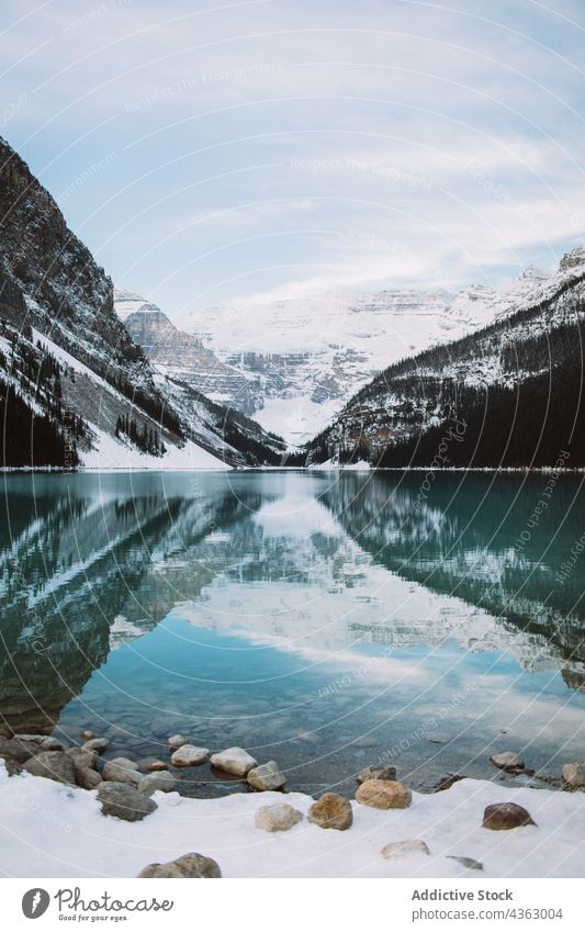 Calm lake reflecting snowy mountains winter reflection shore calm clean sky cloudy lake louise banff national park alberta canada water ridge nature range