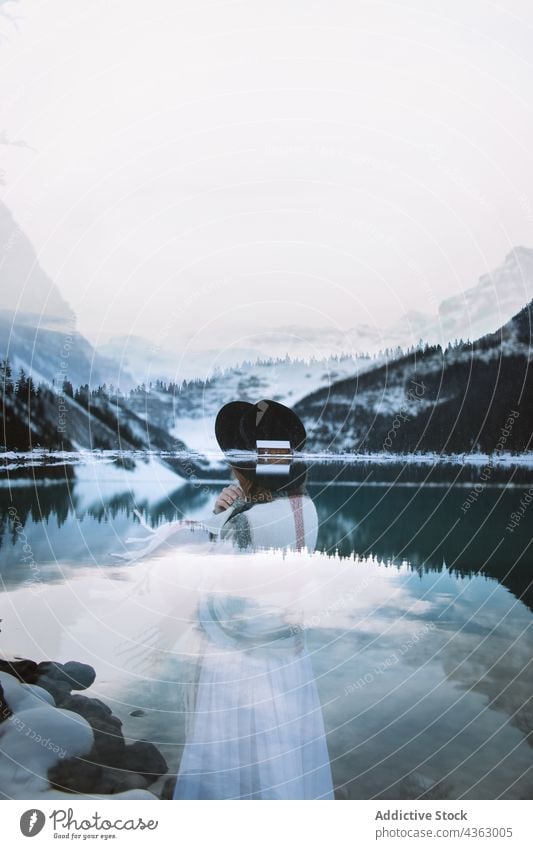 Anonymous dreamy woman near lake in winter mountain rest snow cold nature calm lake louise banff national park alberta canada hat white dress relax tranquil