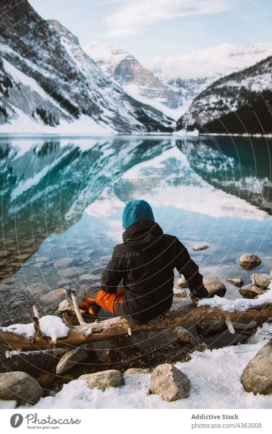 Unrecognizable traveler stretching arms near calm lake shore rest mountain sit nature water winter lake louise banff national park alberta canada cold coast