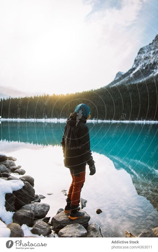 Unrecognizable hiker standing on stones near lake shore morning nature travel winter explore calm lake louise banff national park alberta canada adventure