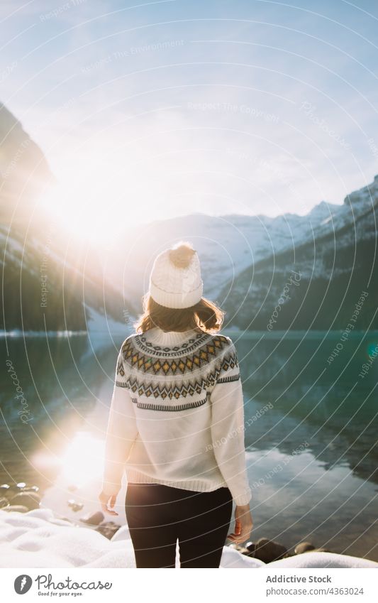 Unrecognizable woman traveler against lake and mountains in morning hiker sunlight nature water shore thoughtful lake louise banff national park alberta canada