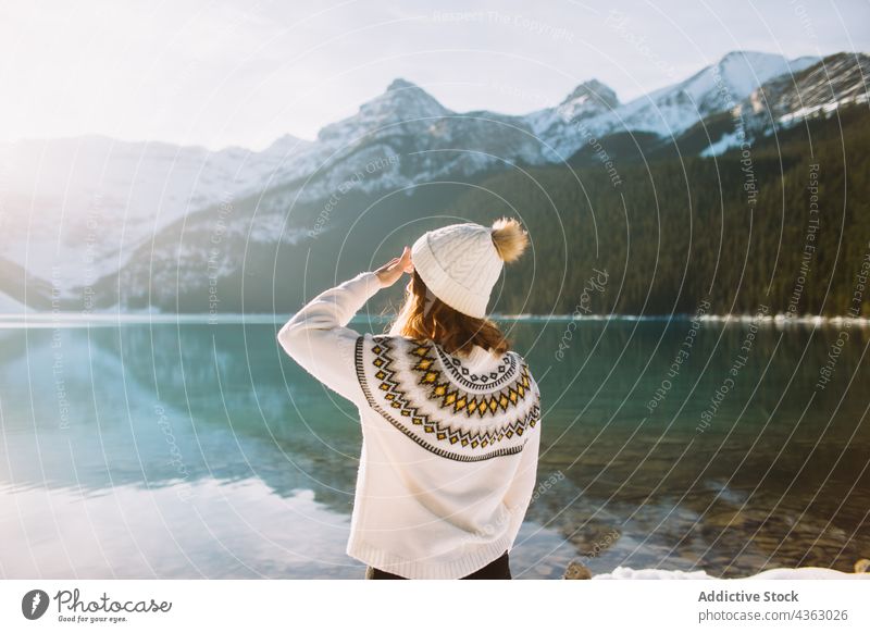 Unrecognizable woman traveler against lake and mountains in morning hiker sunlight nature water shore thoughtful lake louise banff national park alberta canada