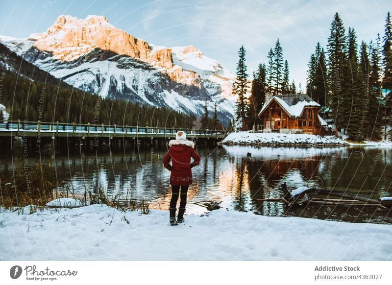 Anonymous woman walking on snowy lake shore near mountain and hut tourist winter admire travel emerald lake british columbia canada banff national park