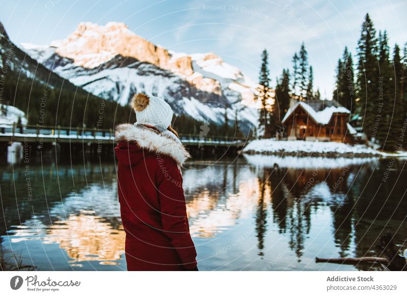 Anonymous woman standing on snowy lake shore near mountain and hut tourist winter admire travel emerald lake british columbia canada banff national park