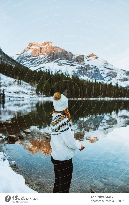 Female traveler resting on lake coast in winter woman shore mountain forest snow nature coniferous emerald lake british columbia canada banff national park