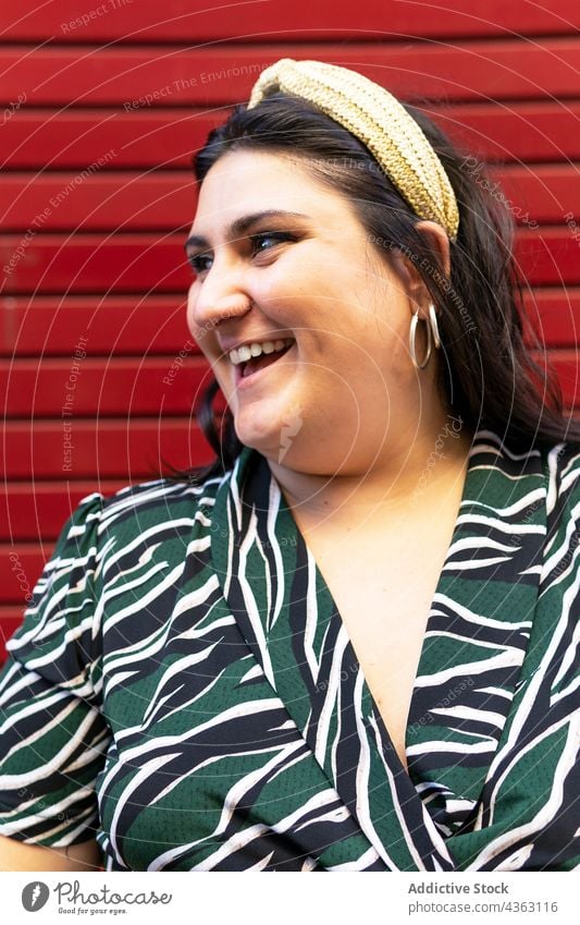 Portrait of happy stylish woman against red wall headband style stripe brunette cheerful having fun fashion long hair young female accessory trendy curvy