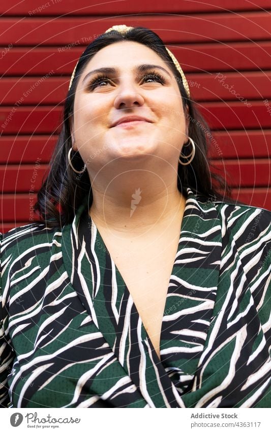 Portrait of happy stylish woman against red wall headband style stripe brunette cheerful having fun fashion long hair young female accessory trendy curvy