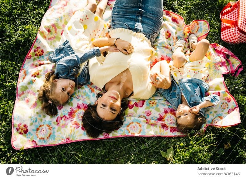 Little siblings with mom resting on blanket in park mother kid together happy summer love daughter similar cute child relationship little children sister alike