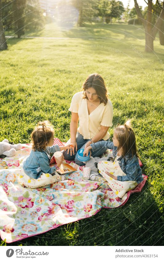 Cheerful mother and kids having picnic in park together summer happy love daughter sibling drink cup child mom relationship little children sister bonding