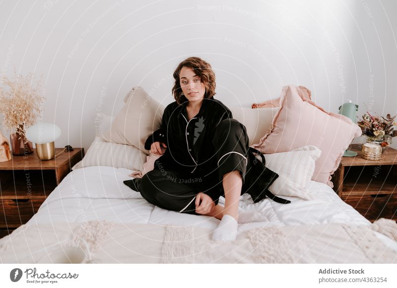 Delicate woman in pajama sitting in bed bedroom tender morning comfort cozy relax soft female awake peaceful sleepwear tranquil serene home nightwear blanket