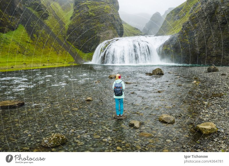 Aerial view of a hiker with backpack in front of the Stjornarfoss waterfall in South Iceland Waterfall Woman stjornarfoss Antenna Icelandic River Nature travel