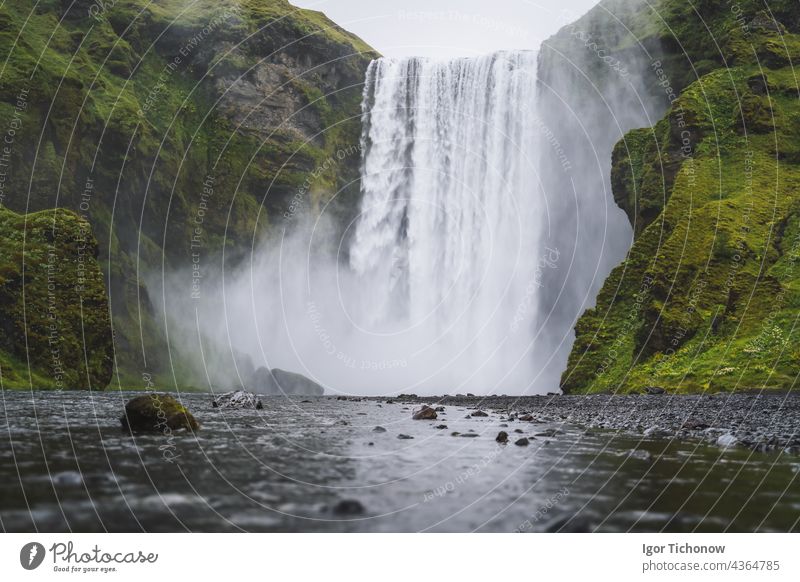 The beautiful waterfall Skogafoss. The most popular destination in Iceland. Water falls down a beautiful valley and is reflected in the river below Fog