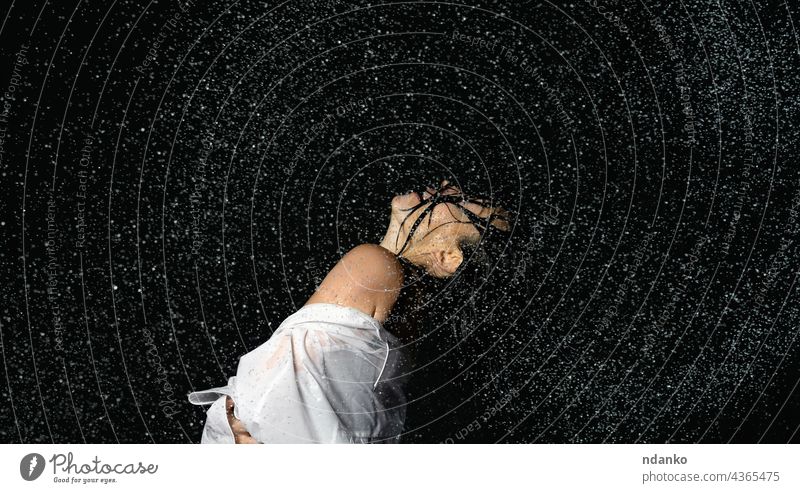 beautiful woman of Caucasian appearance with black hair dances in drops of water on a black background person female dancing motion splash wet beauty fashion