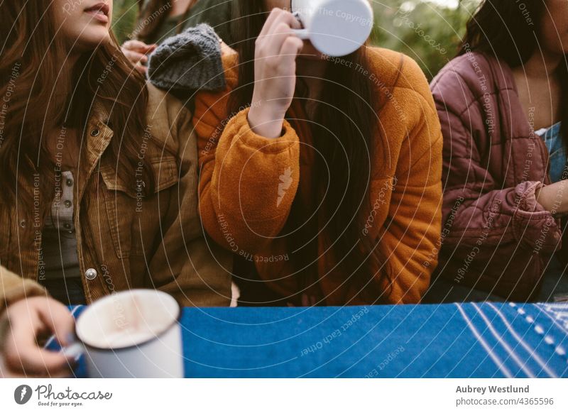 women drinking hot chocolate from mugs at a picnic table autumn blue camping cheers community cook cookware culinary enamel enamelware fall food group heat